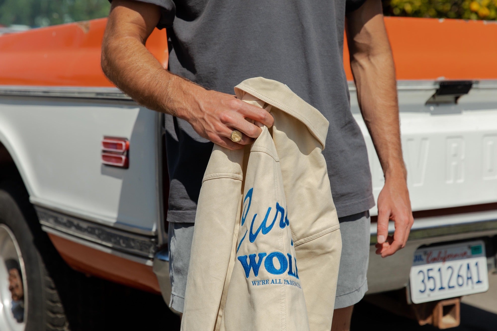 Lower half of man in front of Chevrolet truck holding the Curly Wolf Bronco Jacket