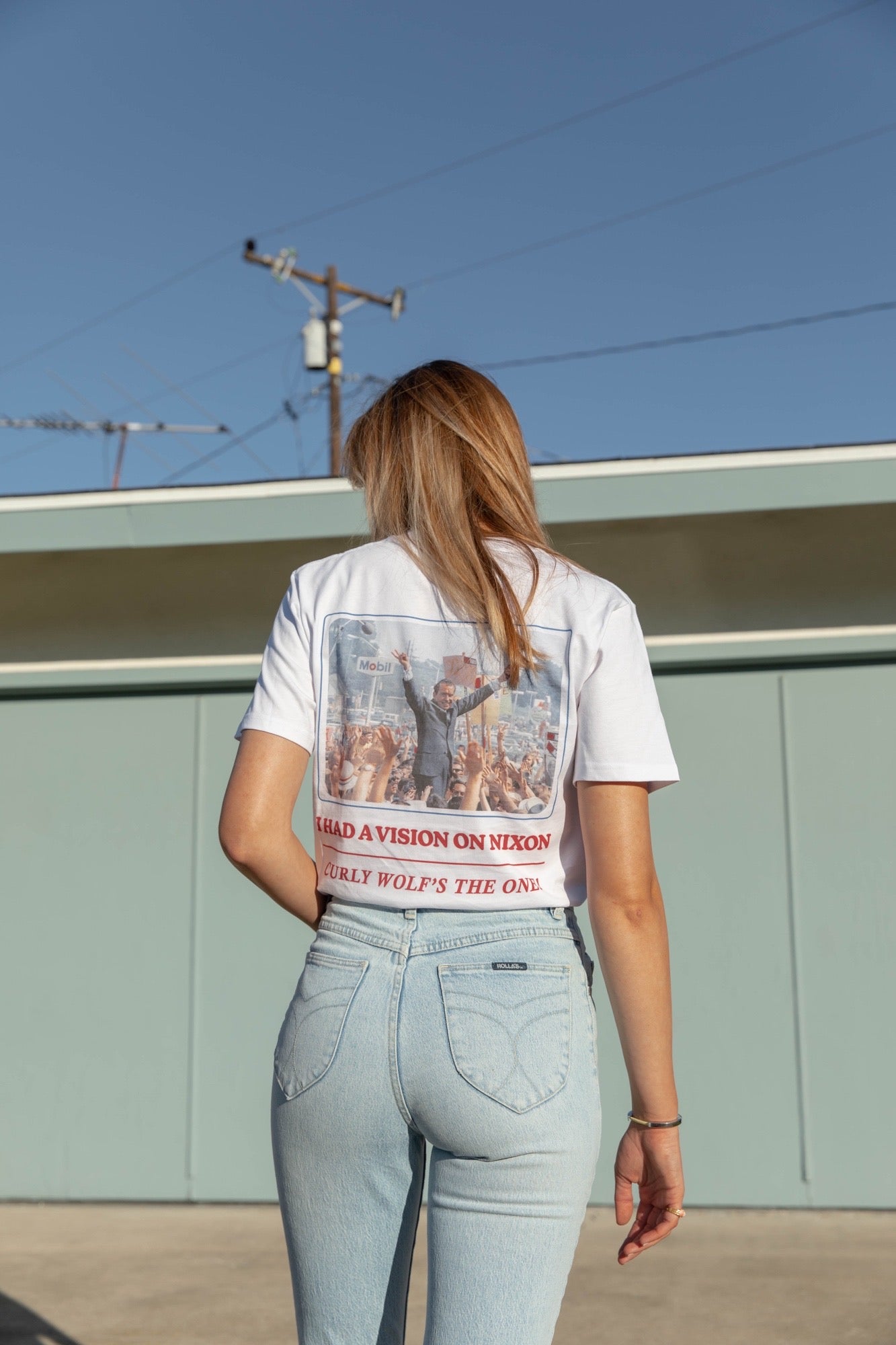 Woman with back towards the camera wearing jeans and Curly Wolf Nixon Tee